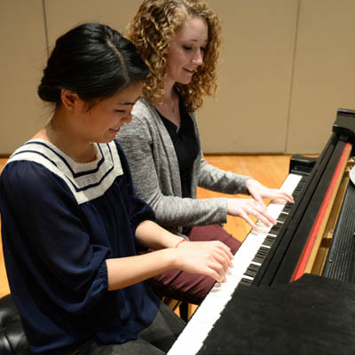 two students playing piano