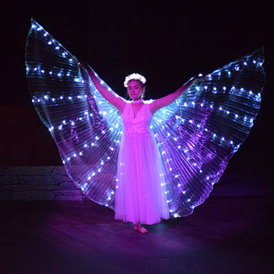 A student on stage in a costume that looks like an angel.