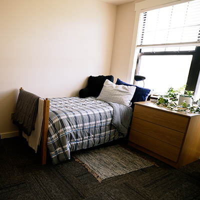 A bed with a blue bed spread in a room in the LLC.