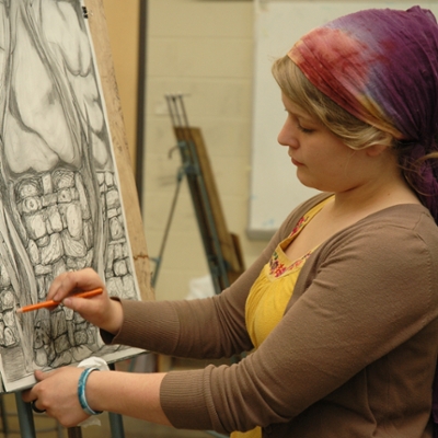 A Washburn art student works on a painting during class in the Art Building.