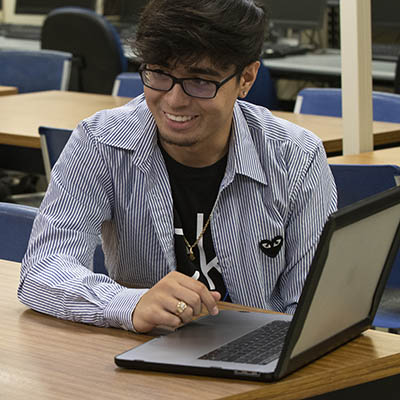 A student smiles while talking with a student over a laptop
