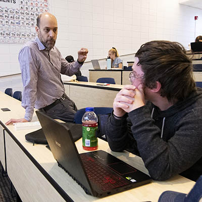 A student and professor talk during class.