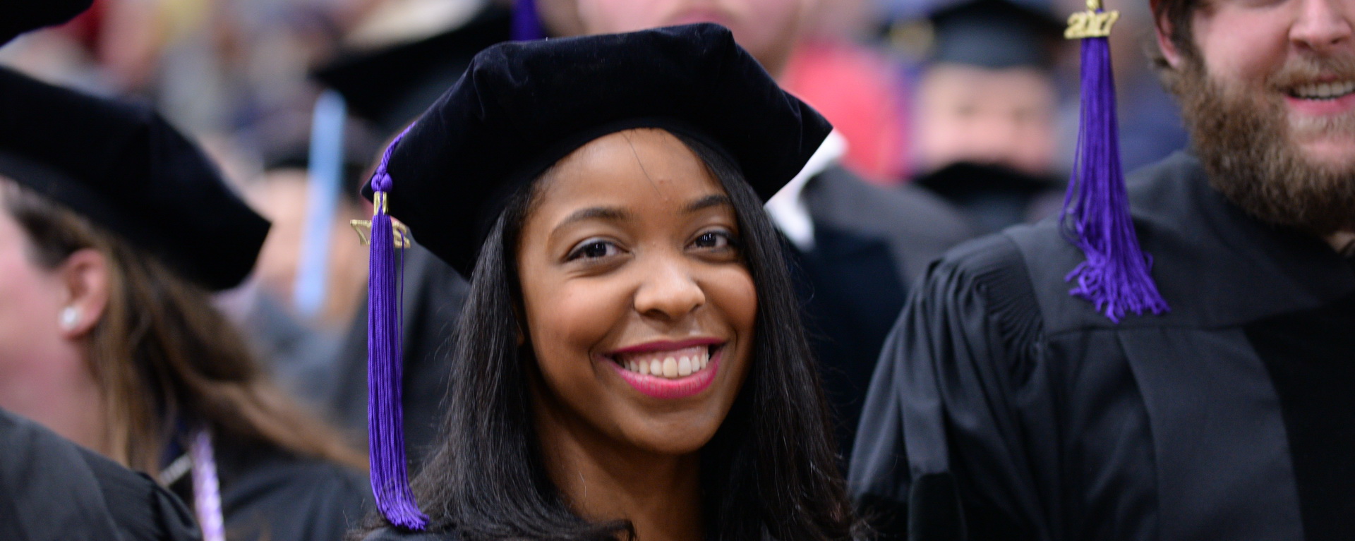 Black female student smiling in graduation regalia