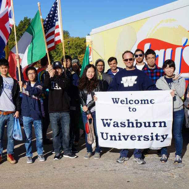 International club group photo holding a sign "Welcome to Washburn University"