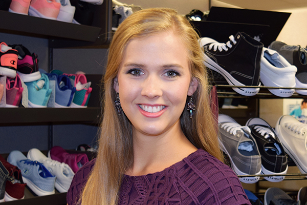 business student smiling with shoes on racks behind