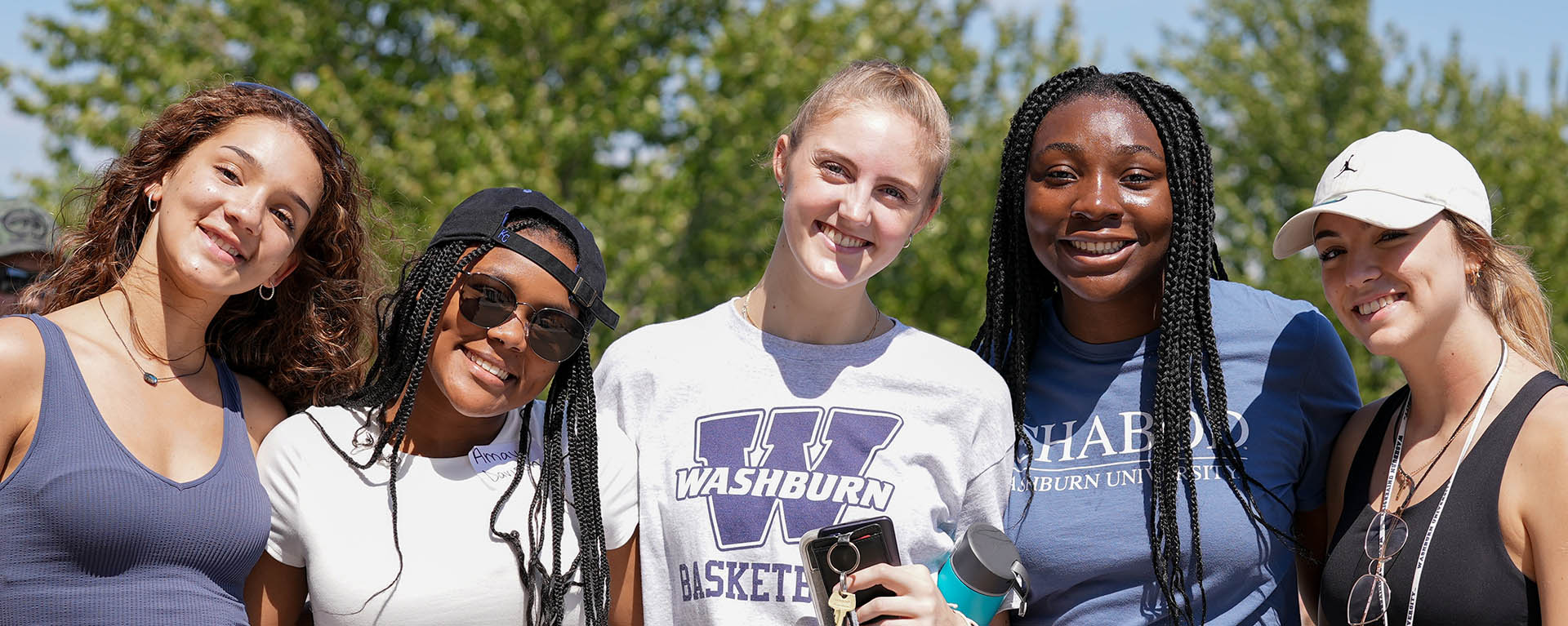 A group of Washburn students smile for a photo while at a football tailgate.