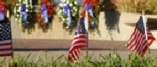 American flags foreground with memorial wreaths in background