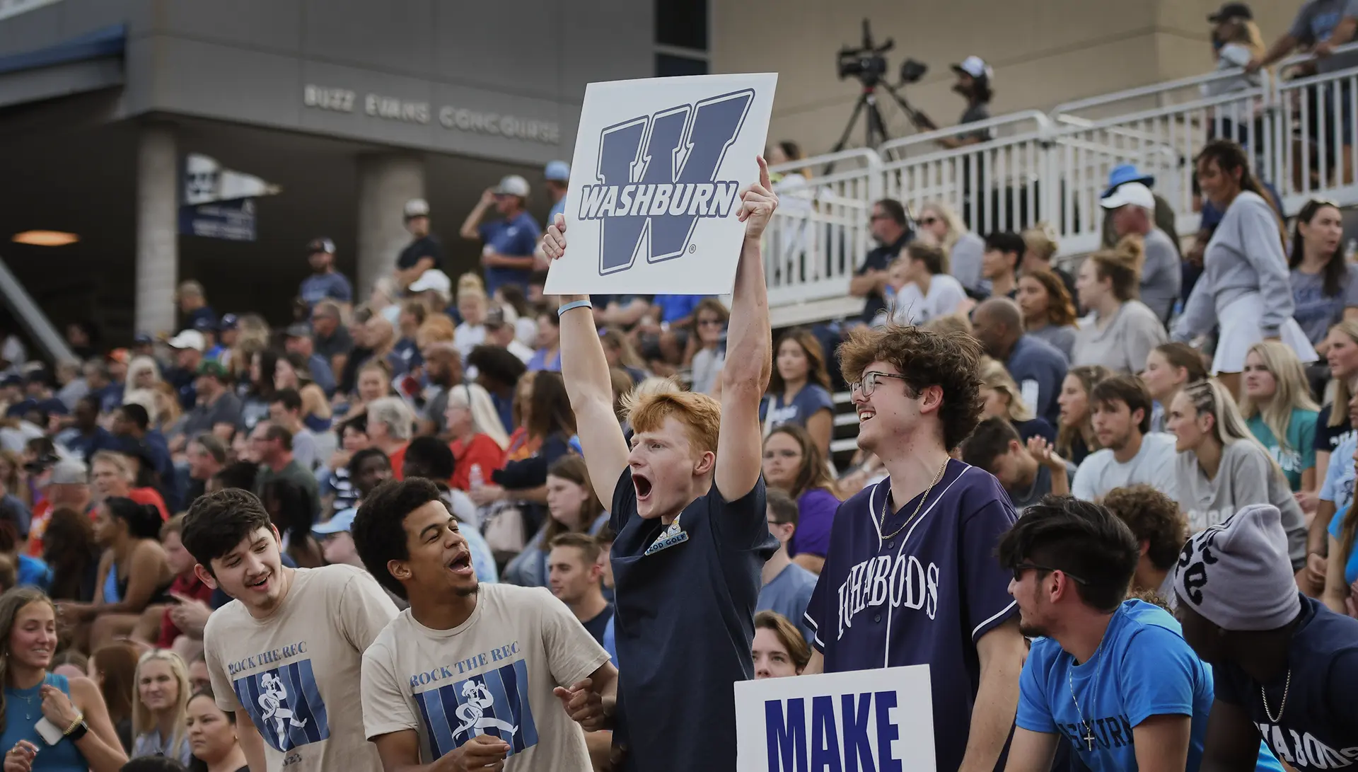 Students cheer in the stands at a football game.