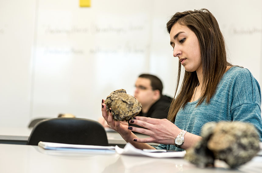 student inspects fossil in classroom