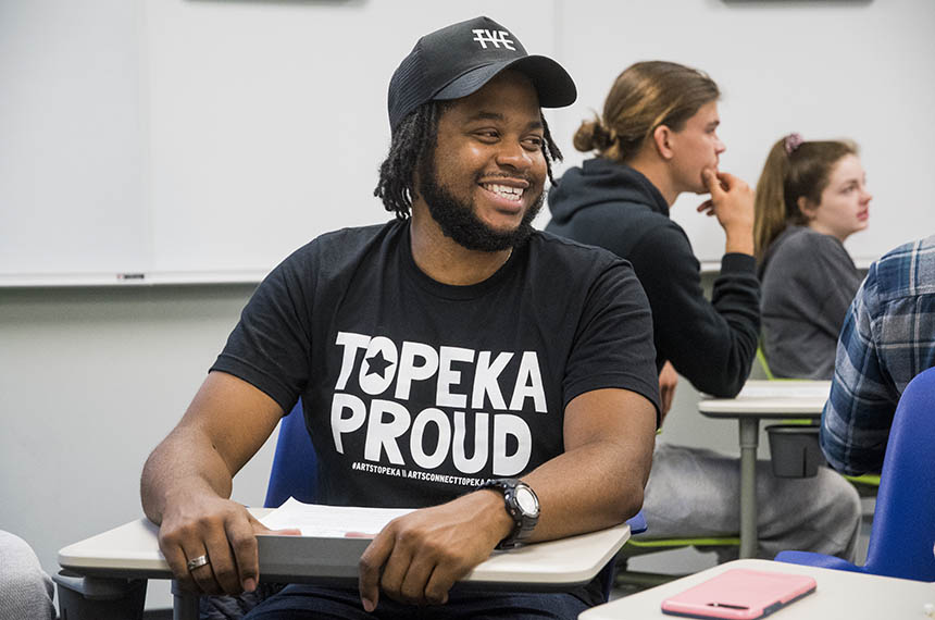 student smiles while wearing a Topeka Proud shirt in classroom.