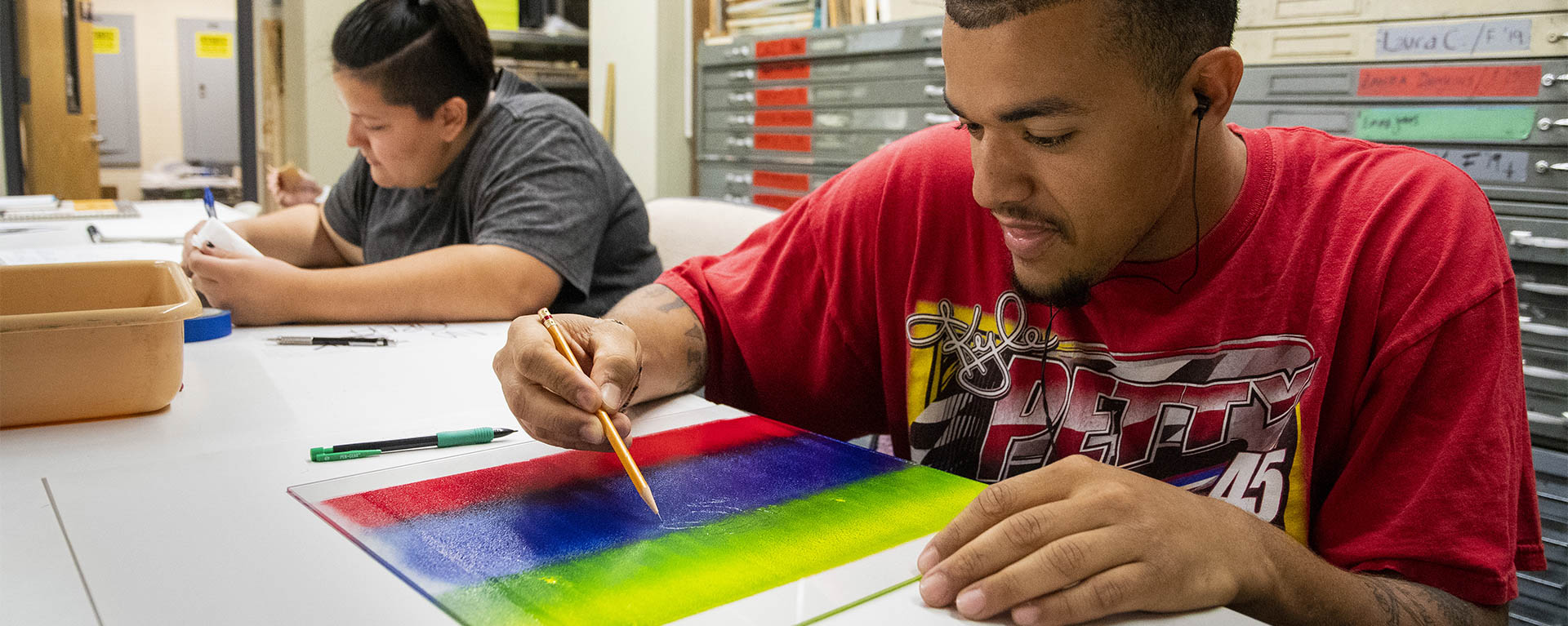 Two students work on their ink etching projects while in class.