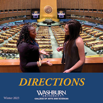A student speaks with a policy advisor in the United Nations General Assembly hall.