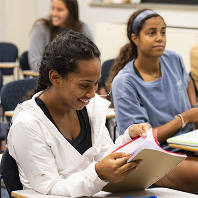 Student looking through notebook in class while smiling