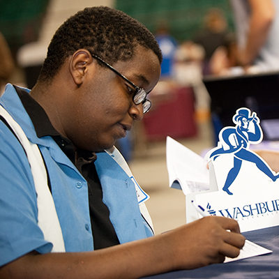 A Washburn student fills out paperwork during a recruiting event.