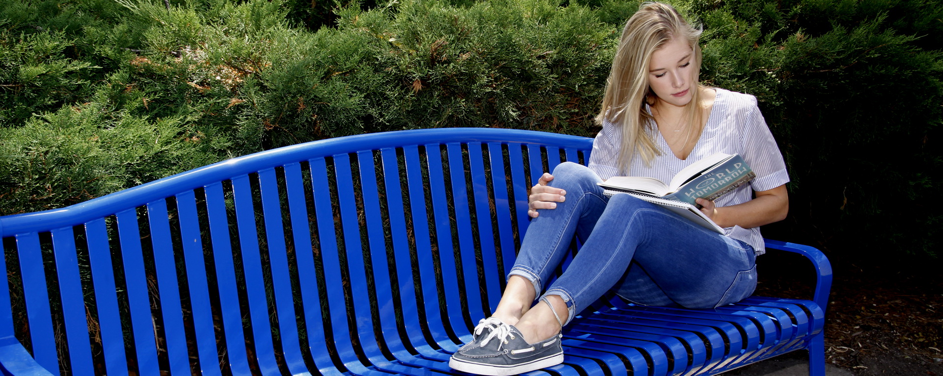 female student on bench reading a book