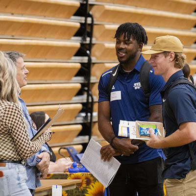 Two students wearing Washburn shirts talk with a potential employer at a booth.