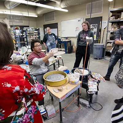 A Washburn student explains a ceramics conept to high school students.