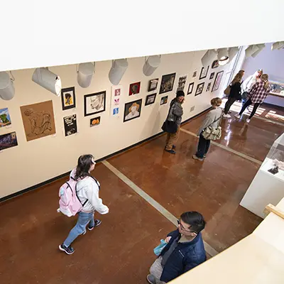 Students walk through a display of high school art competition art work.