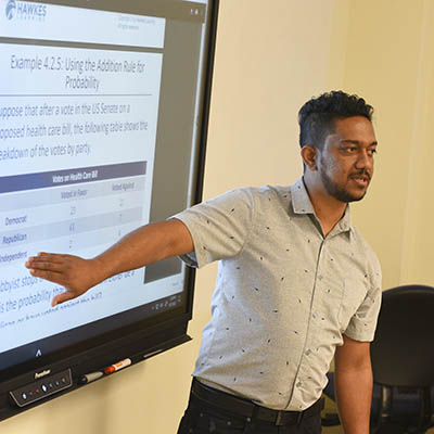 A professor gestures at the screen while teaching.