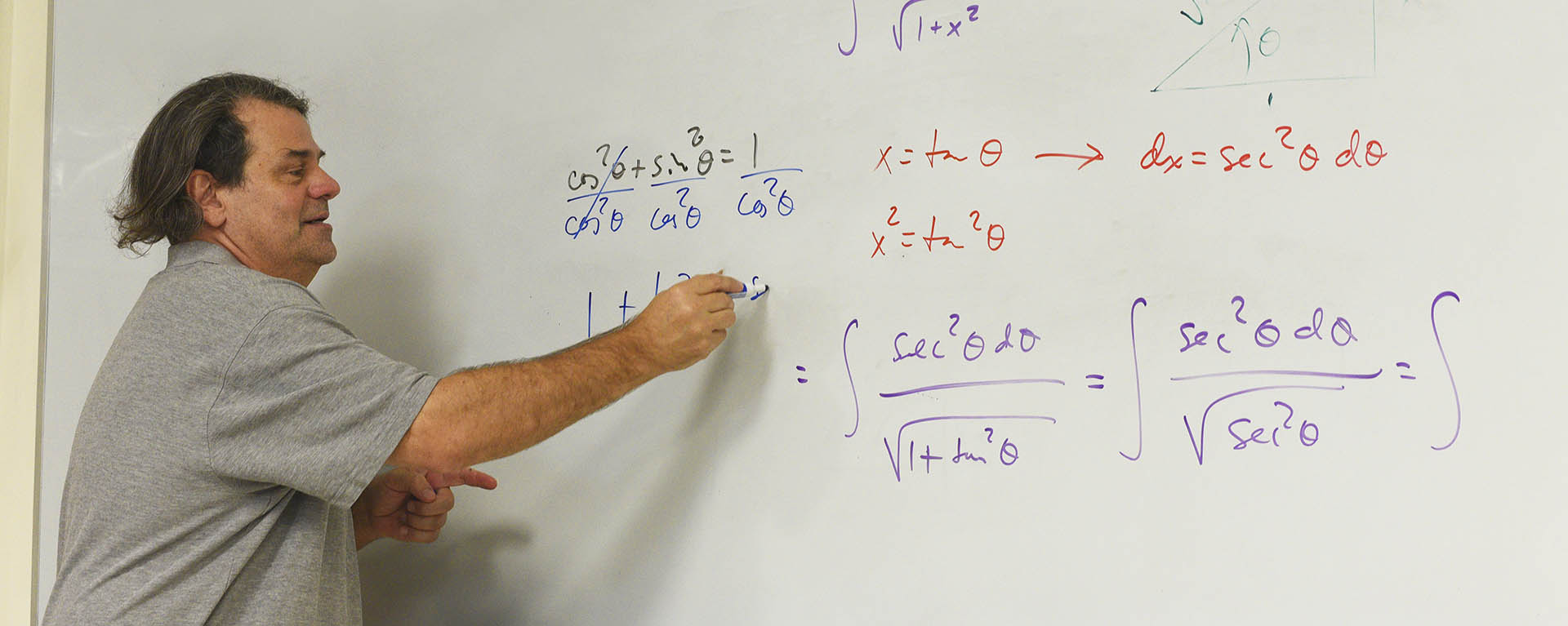 A math professor teaching in front of a white board.