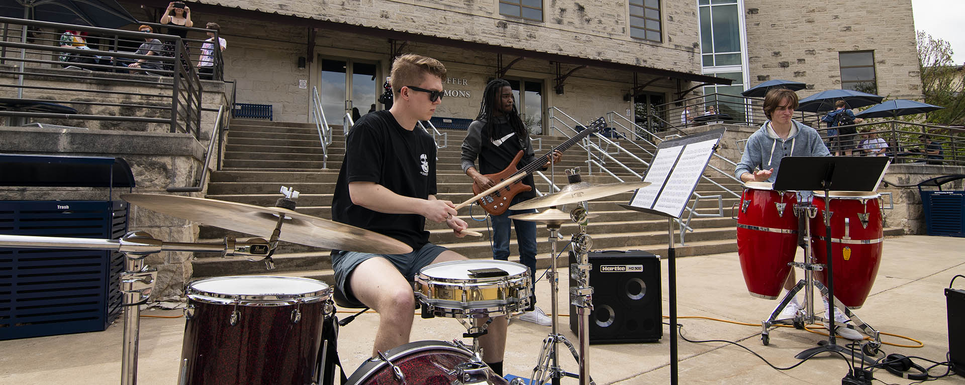Students playing drums and guitars outside of the Washburn student union.