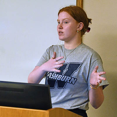 A gestures while giving a narrating a story to the class.