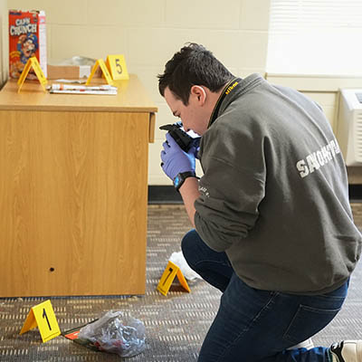 A forensic student examines a mock crime scene.