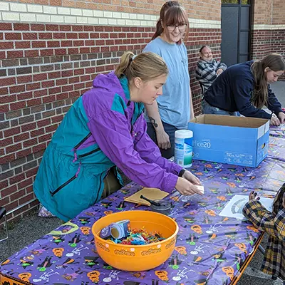 A student club member hands out candy at a trick or treat table.