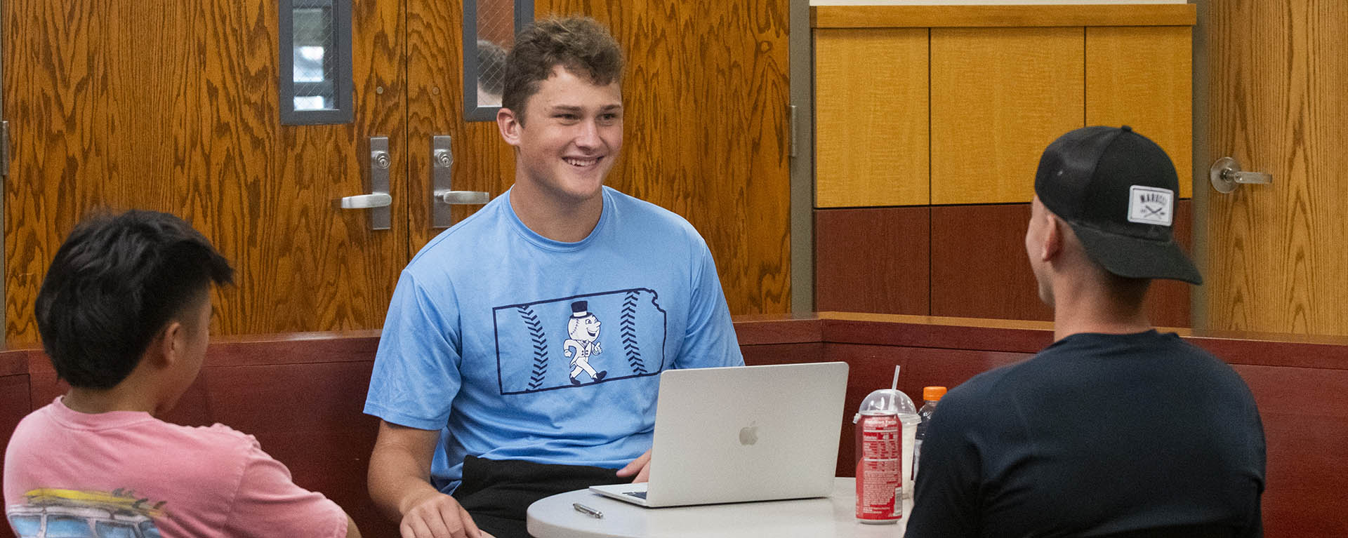 Three student athletes talk while studying together.