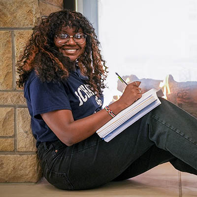 A student studies in front of a fireplace.