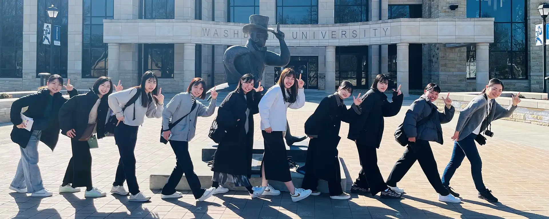 students smiling and walking like Ichabod in front of Ichabod statue at Morgan Hall